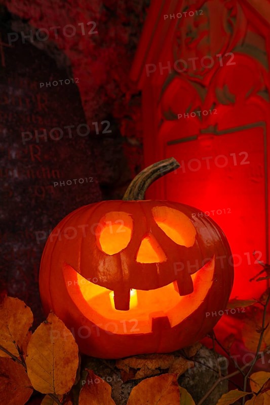 Halloween pumpkin with candlelight in the cemetery, illuminated red and spooky