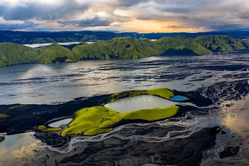 Turquoise-coloured crater lake with moss-covered crater rims in the Icelandic highlands, surrounded by glacial rivers, Iceland