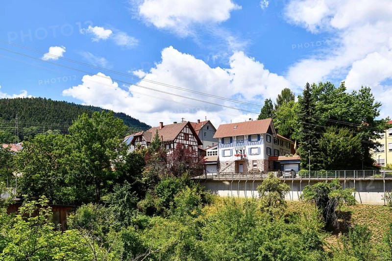 Forbach, Germany - July 12th 2025: Buildings surrounded by trees in Forbach. Scenic summer view of Black Forest town under blue sky