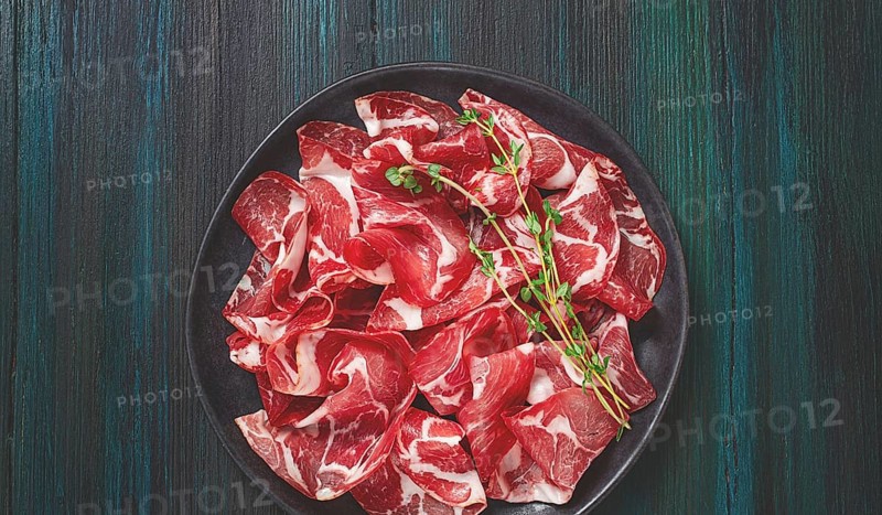 Plate with sliced cured meat, pork neck, prosciutto coppa, Italian delicacy