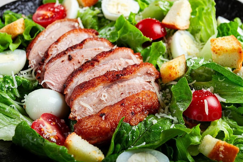 Caesar salad, with duck breast, on a black plate, on a light background, homemade, no people