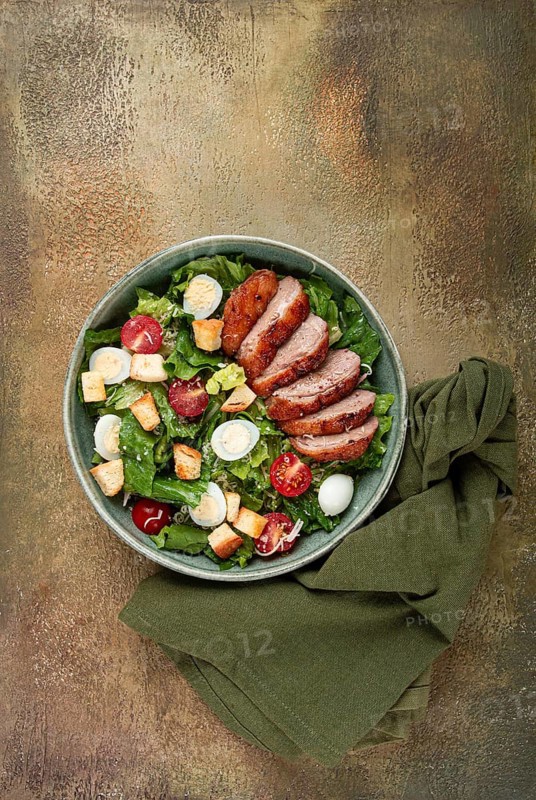 Caesar salad, with duck breast, on a green plate, homemade, no people