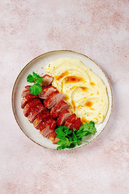 Roast duck breast, sliced with mashed potatoes, on a white plate, close-up, no people