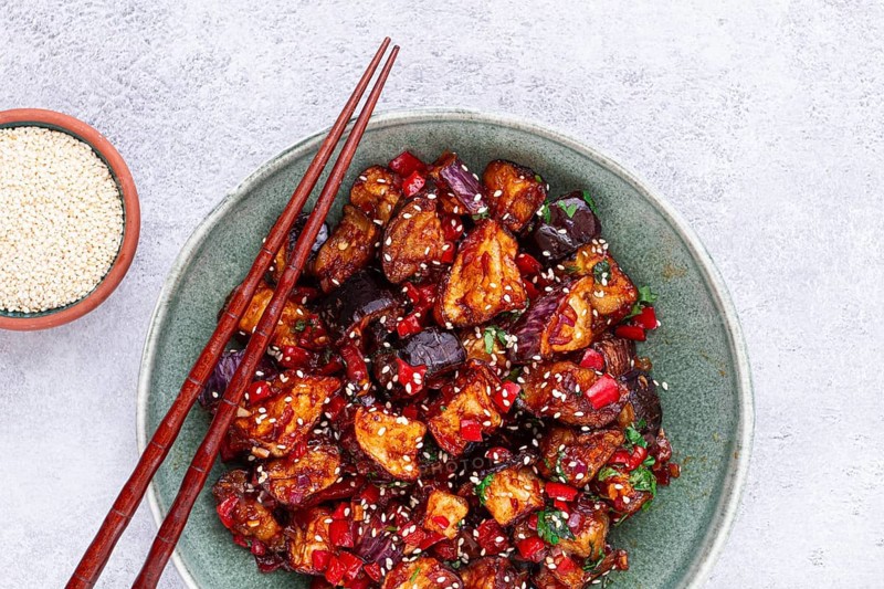 Fried eggplant, Chinese style, in sweet and sour sauce, with pepper and sesame seeds, in a green bowl