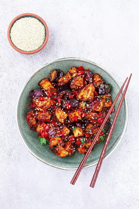 Fried eggplant, Chinese style, in sweet and sour sauce, with pepper and sesame seeds, in a green bowl