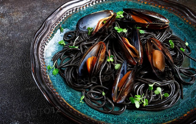 Black spaghetti, nori pasta, with mussels, top view, on a dark background, homemade, no people