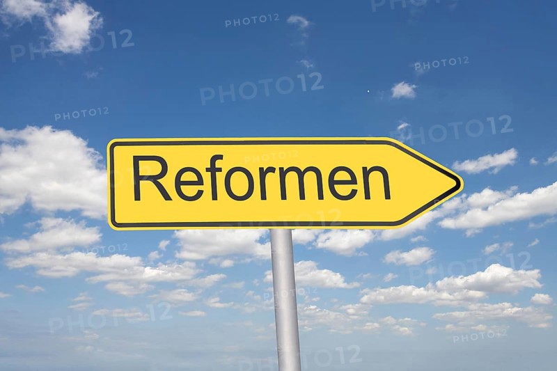 (Photomontage) Directional arrow with the inscription REFORMEN in front of a blue sky
