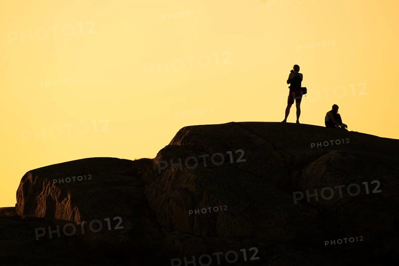 Silhouette of two tourists photographing the sunset on a rock, Smögen, Smögenbryggan, Västra Götalands Län, Bohuslän, Sweden