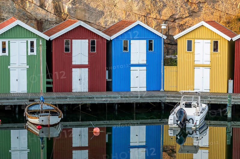 Colourful boathouses and boats in the calm water in front of rocks in the harbour of Smögen, Smögenbryggan, Västra Götalands Län, Bohuslän, Sweden