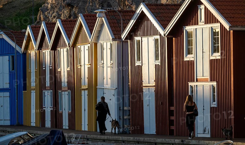 Strollers in front of colourful boathouses in the harbour of Smögen, Smögenbryggan, Västra Götalands Län, Bohuslän, Sweden