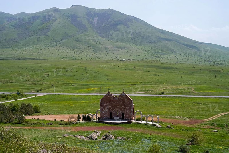 Small stone church in a vast green landscape in front of a mountain with clouds, Saint Trinity Altar of Hope, Aparan, Aragazotn Province, Armenia