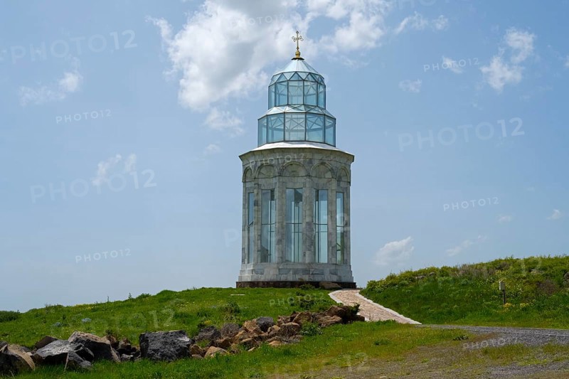 Glass church on a hill path, crowned by a golden cross under a cloudy sky, Garden of Eternity, Aparan, Aragazotn Province, Armenia