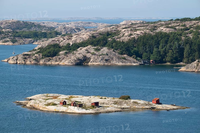 Archipelago landscape with rocks and an offshore archipelago island with falun red woodsheds, Fjällbacka, Bohuslän, West Sweden, Sweden