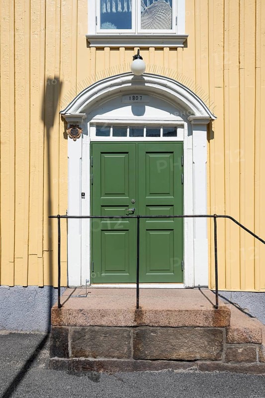 Entrance of a light yellow wooden house with a green door and white door frame, Fjällbacka, Bohuslän, West Sweden, Sweden