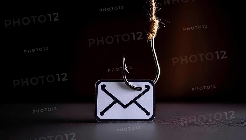 A picture of an email with a hook on it. The hook is attached to the envelope, and the envelope is on a table. Concept of danger and urgency, AI generated