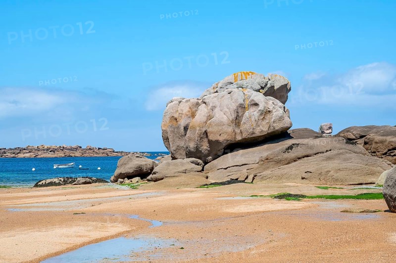 Spectacular pink granite rocks, sculpted by wind and sea, pile up on the beach of the Cote de Granit Rose, while the clear, turquoise-blue water reveals seaweed and light-coloured sand on the seabed at low tide, Tregastel, Cotes-d'Armor department, Brittany region, France