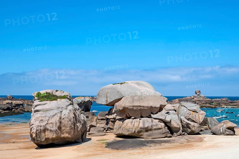 Spectacular pink granite rocks, sculpted by wind and sea, pile up on the beach of the Cote de Granit Rose, while the clear, turquoise-blue water reveals seaweed and light-coloured sand on the seabed at low tide, Tregastel, Cotes-d'Armor department, Brittany region, France