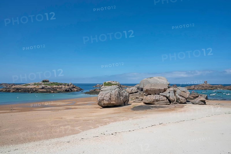 Spectacular pink granite rocks, sculpted by wind and sea, pile up on the beach of the Cote de Granit Rose, while the clear, turquoise-blue water reveals seaweed and light-coloured sand on the seabed at low tide, Tregastel, Cotes-d'Armor department, Brittany region, France