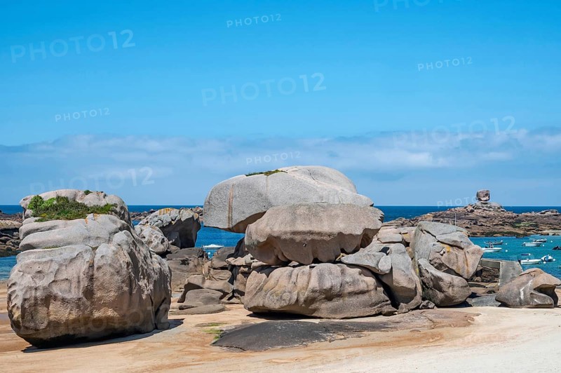 Spectacular pink granite rocks, sculpted by wind and sea, pile up on the beach of the Cote de Granit Rose, while the clear, turquoise-blue water reveals seaweed and light-coloured sand on the seabed at low tide, Tregastel, Cotes-d'Armor department, Brittany region, France