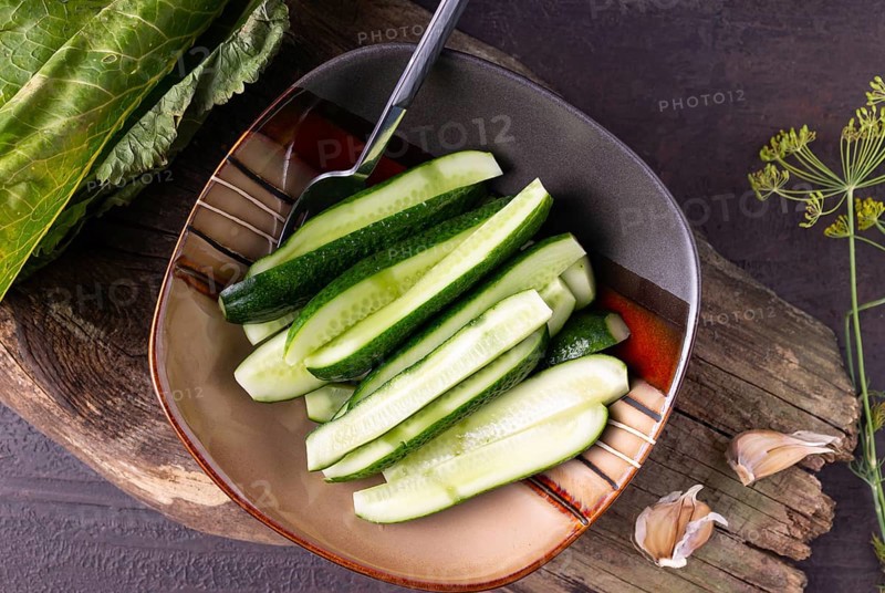 Lightly salted cucumbers in a square plate on a wooden background