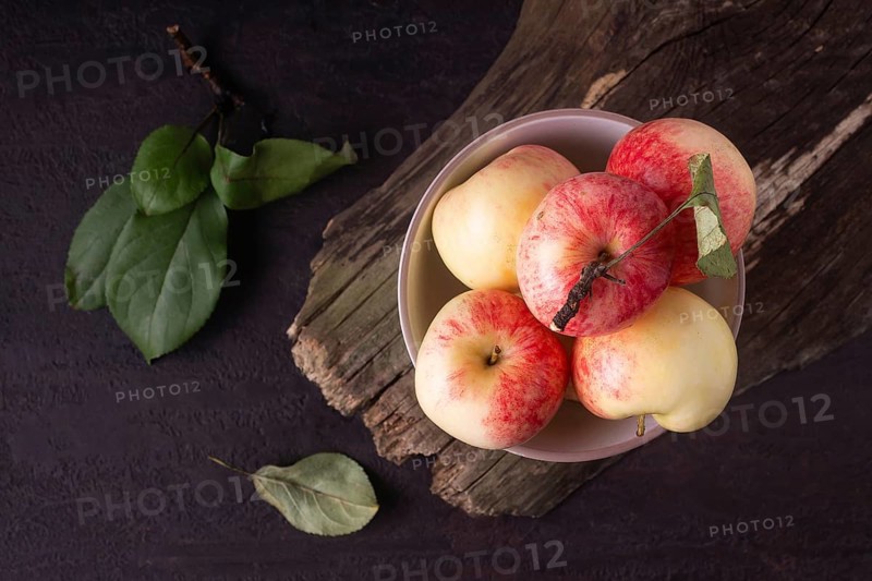 Apples lie in a round white plate on a wooden background