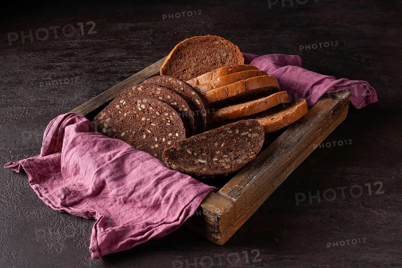 Healthy bread with sprouted grains lies in a wooden box on a pink cloth
