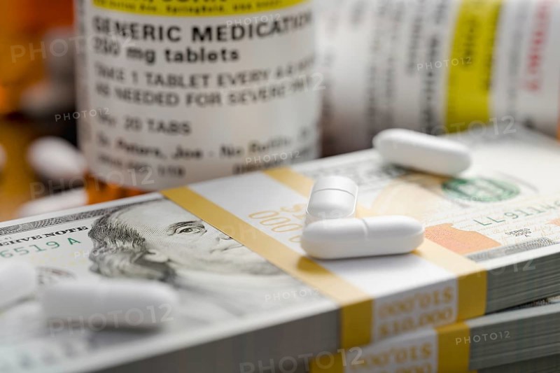 Prescription medicine bottles and pills next to stacks of 100 dollar bills