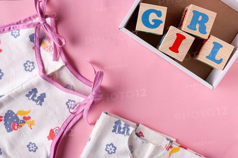Clothes for a newborn girl and wooden cubes with letters Girl