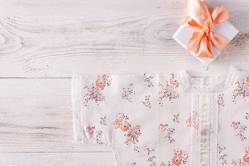 Shirt for newborn toddler and gift box on white wood
