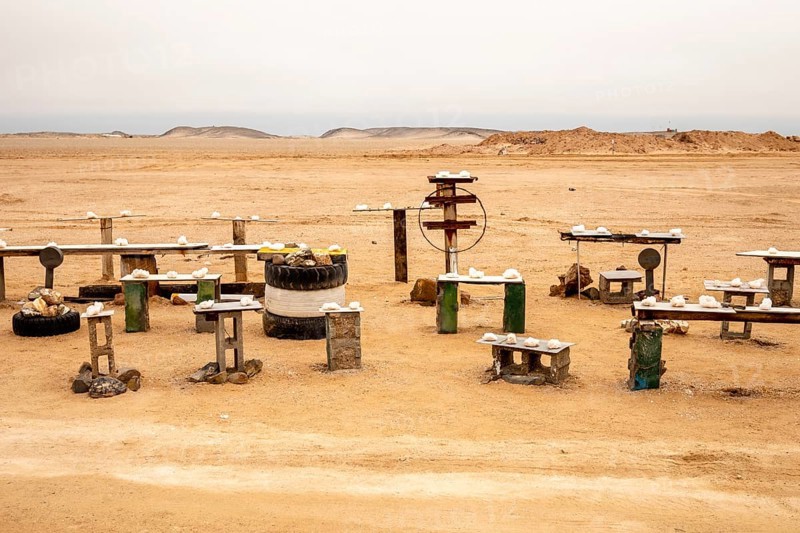 Pink salt displayed on wooden stands along the road to Namib-Naukluft National Park and Sandwich Harbour, Namibia, set against a desert landscape