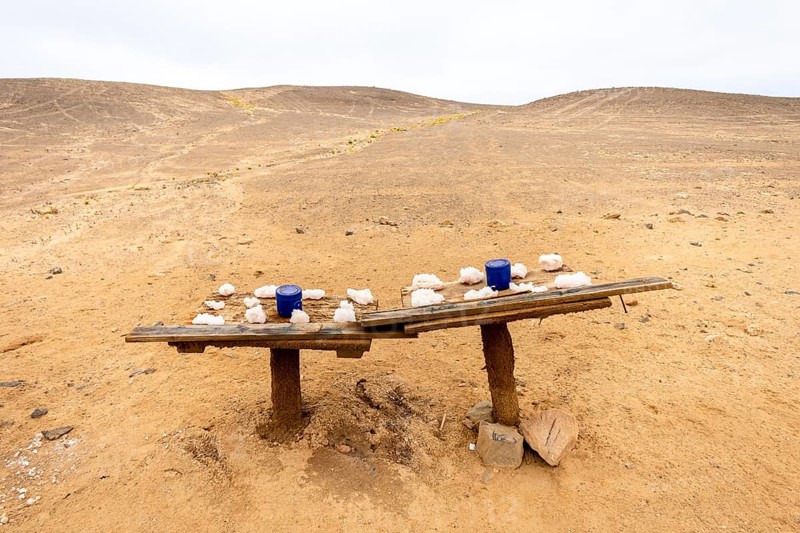 Pink salt displayed on wooden stands along the road to Namib-Naukluft National Park and Sandwich Harbour, Namibia, set against a desert landscape