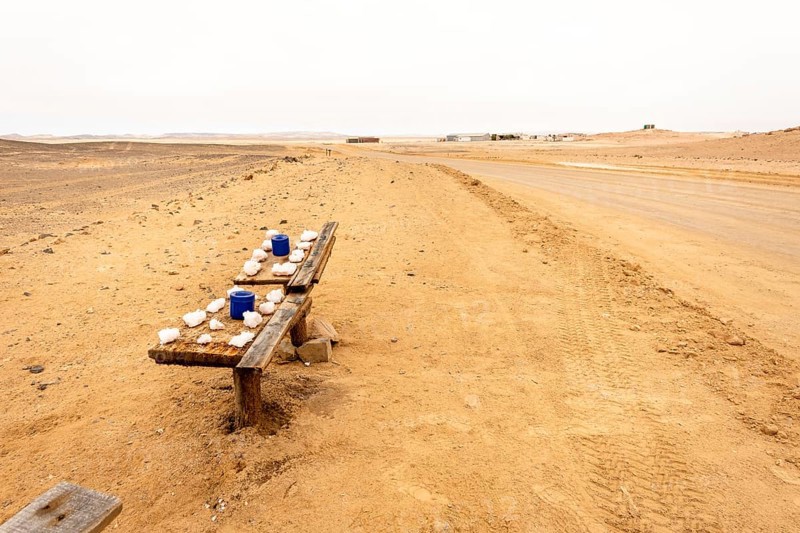 Pink salt displayed on wooden stands along the road to Namib-Naukluft National Park and Sandwich Harbour, Namibia, set against a desert landscape