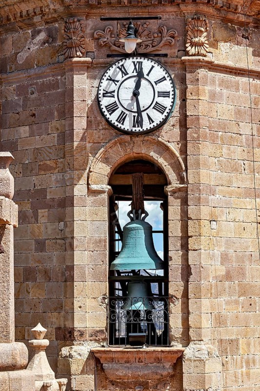Detail of a clock tower with a large clock and a visible bell in a colonial building, The churches of the city of Potosi in Bolivia
