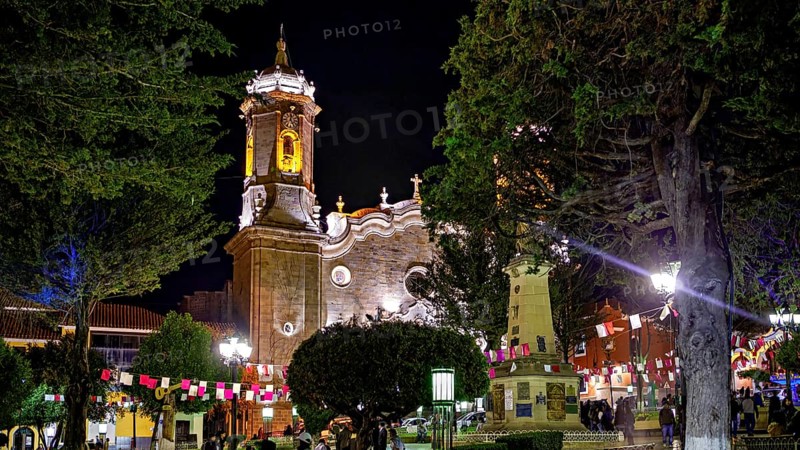 An illuminated church at night decorated with festive activities and flags, surrounded by trees, The churches of the city of Potosi in Bolivia