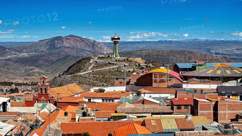 View of orange roofs with a modern building and an antenna in a mountainous environment, view over the city of Potosi in Bolivia