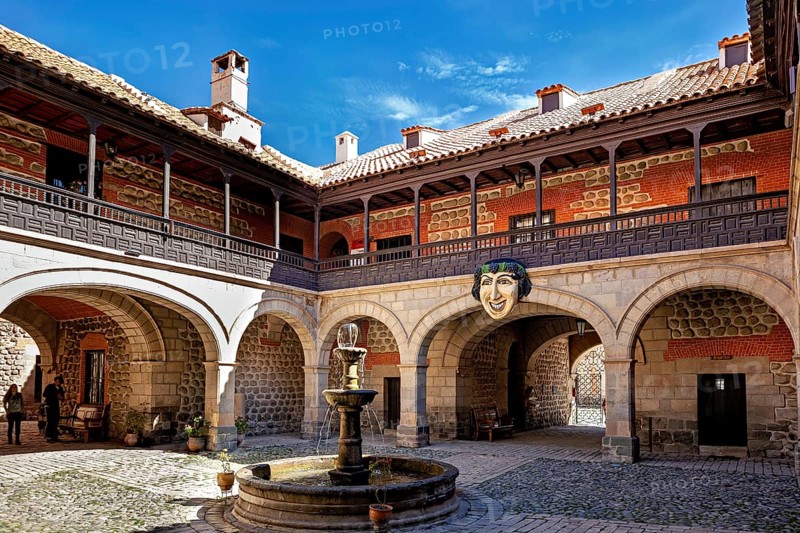 A historic courtyard with a central fountain, surrounded by colonial architecture and stone walls under a blue sky, The courtyard of the museum of the city of Potosi in Bolivia