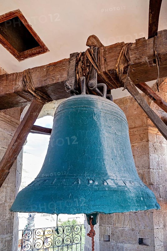 Large bell in an old tower made of wood and stone, with a bright sky in the background, The large bell of Potosi Cathedral in Bolivia