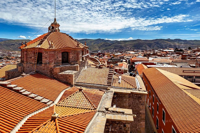 Colonial building with traditional roof tiles and mountain backdrop under a blue sky, The roof of Potosi Cathedral in Bolivia