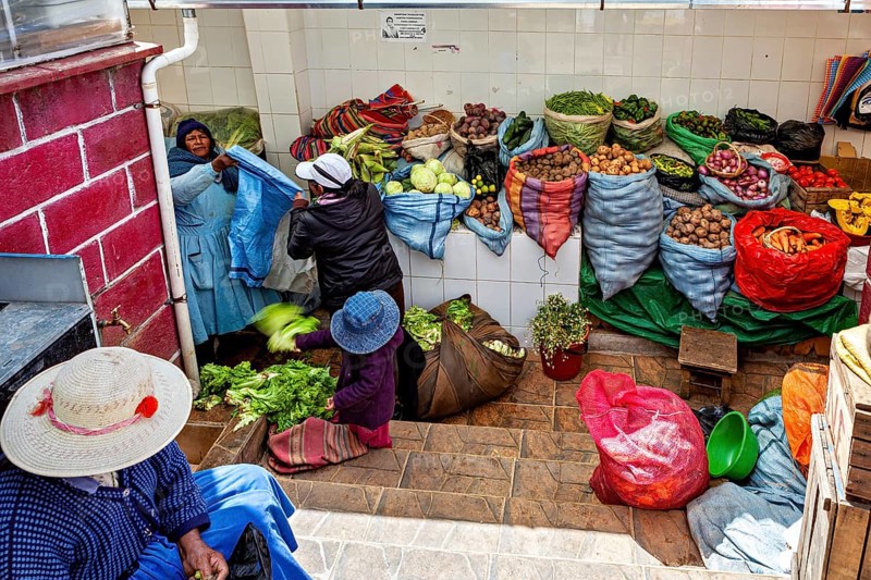 Women arranging vegetables in colourful sacks at a market stall in Bolivia, selling goods in the market halls of Potosi in Bolivia