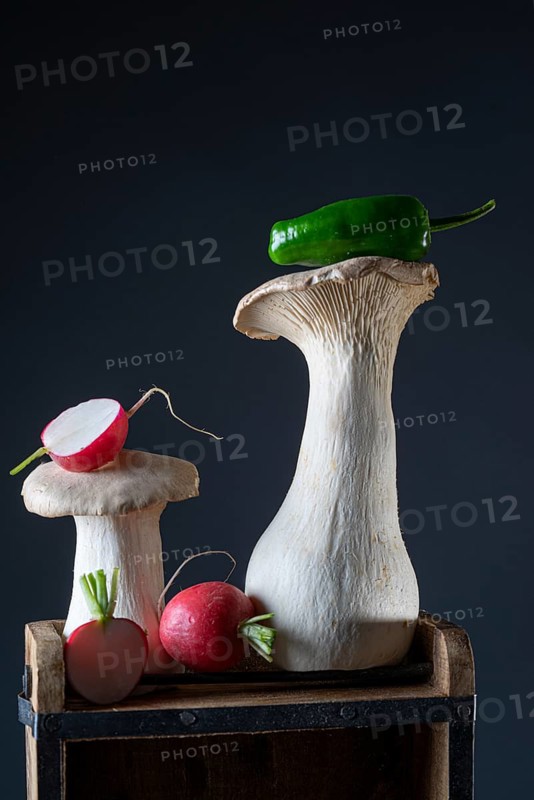 oyster mushrooms with radishes and chillies on a wooden crate against a dark background