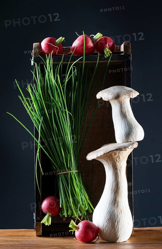 oyster mushrooms with radishes, chives and chillies on a wooden crate against a dark background