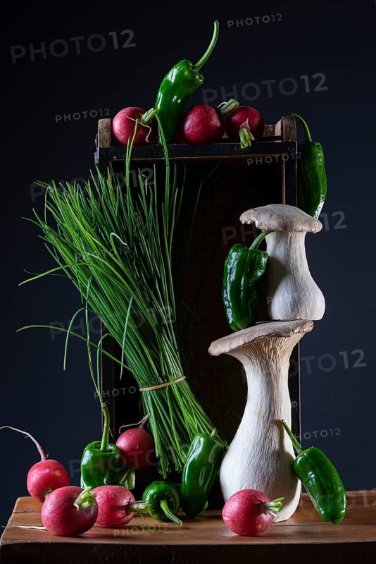 oyster mushrooms with radishes, chives and chillies on a wooden crate against a dark background