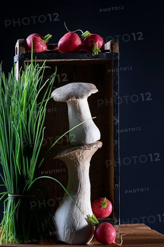 oyster mushrooms with radishes and chives in a wooden crate against a dark background