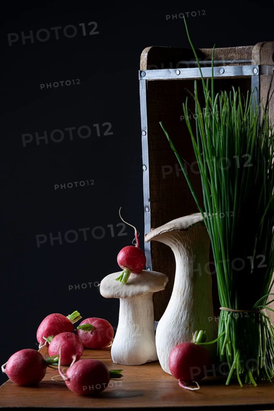 oyster mushrooms with radishes and chives in front of a wooden crate with a dark background