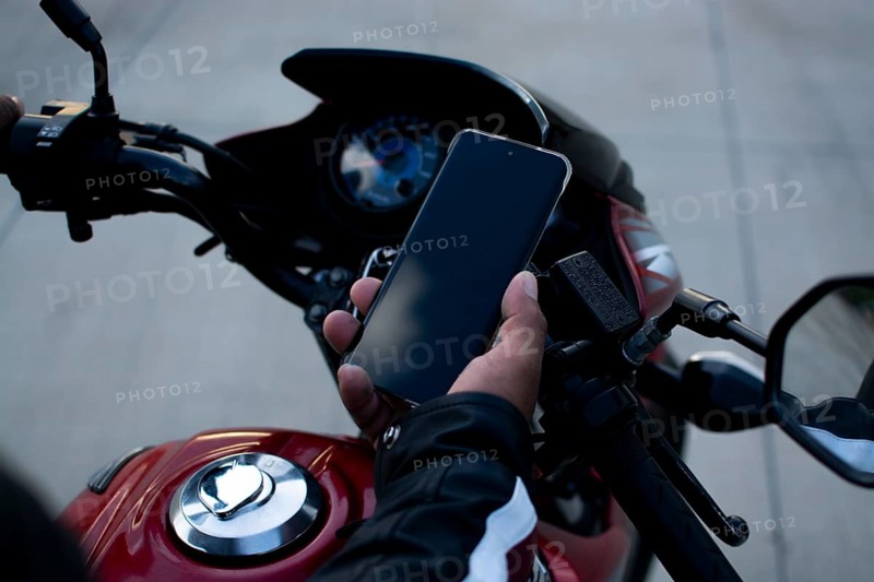 Close up of a motorcyclist holding a phone. Biker using his phone on a motorcycle