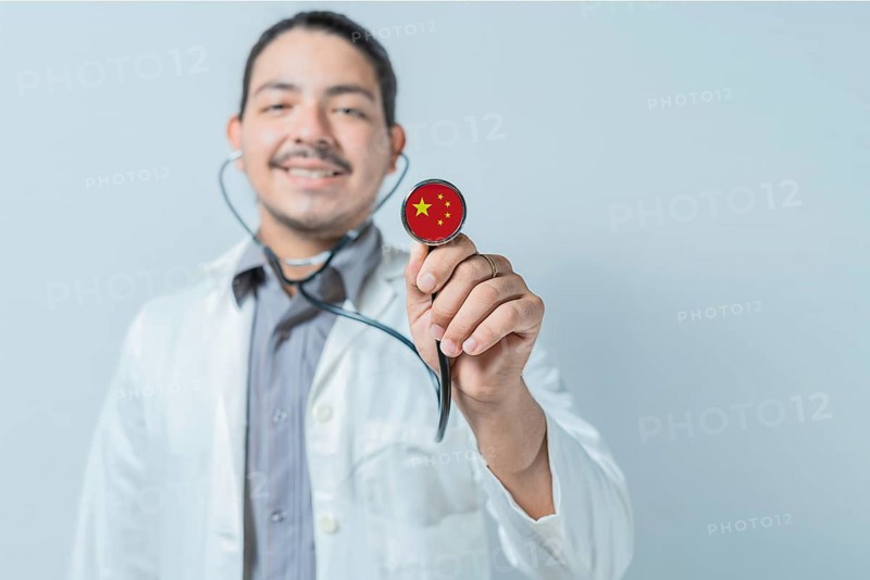 Smiling doctor showing stethoscope with China flag. China national healthcare