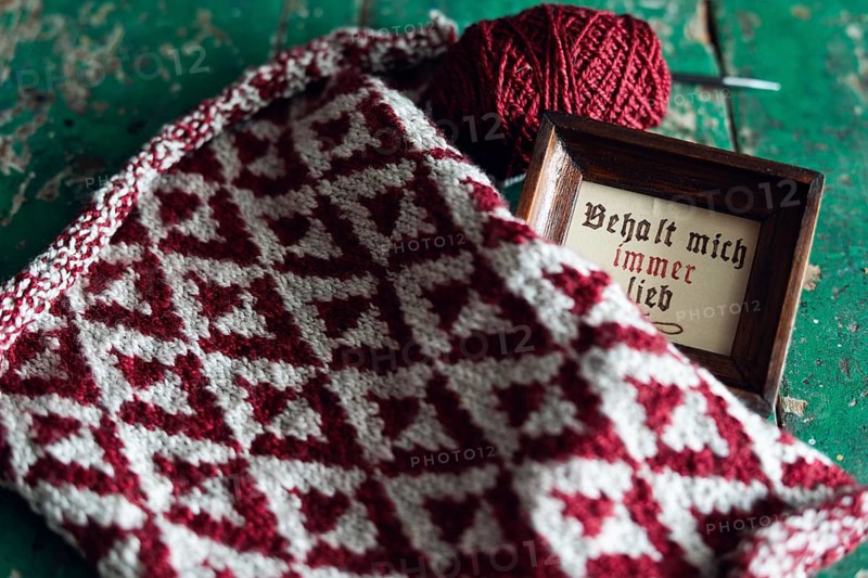 Knitted piece with ball of wool and framed picture with the lettering Behalt ich immer lieb