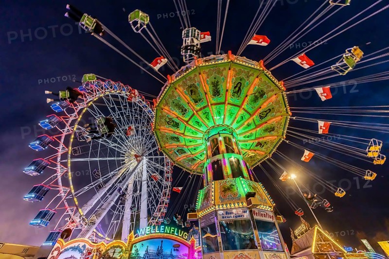 Folk festival time in Stuttgart. Ferris wheel and chain carousel in the evening. The 178th Cannstatter Volksfest on the Wasen is one of the most important traditional festivals in Germany. In addition to the large festival tents, the Wasen is characterised by fairground attractions. Around 320 showmen, festival hosts and market traders expect around four million visitors. Bad Cannstatt, Stuttgart, Baden-Württemberg, Germany