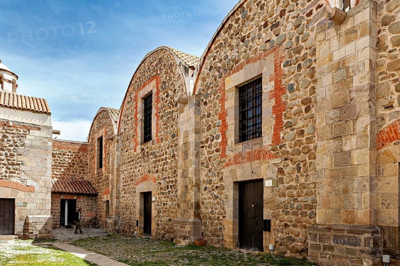 Historic stone buildings with tile accents and curved roofs under a blue sky, The historical museum of Potosi in Bolivia