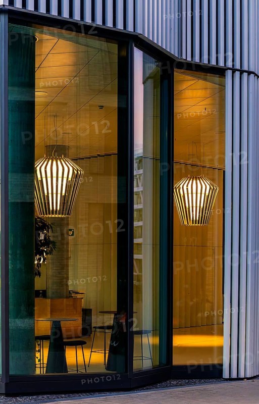 The picture shows the interior of a modern Berlin restaurant, taken in the evening, the scene is characterised by modern lighting fixtures reminiscent of large, glowing light bulbs, Berlin, Germany